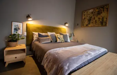a bedroom with a large bed with a wooden headboard at The Lazy Leopard Lodge in Hoedspruit