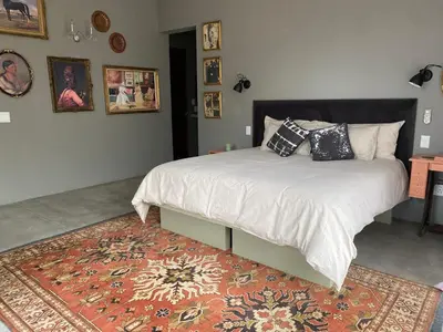 a bedroom with a bed with pillows and a rug at The Lazy Leopard Lodge in Hoedspruit