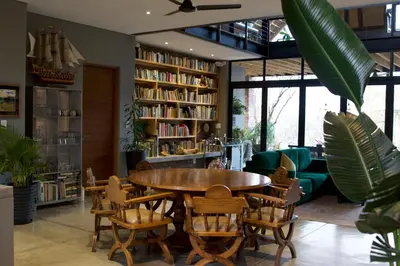 a library with a table and chairs and bookshelves at The Lazy Leopard Lodge in Hoedspruit