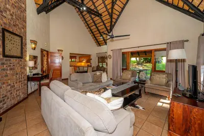 a living room with white couches and a television at Kruger Park Lodge Unit No. 246 in Hazyview