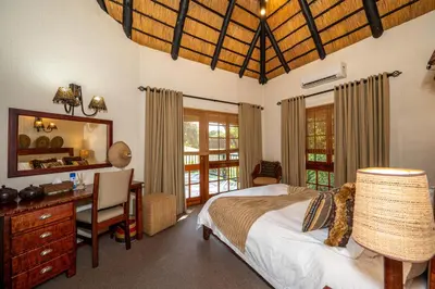 a bedroom with a bed and a desk and a mirror at Kruger Park Lodge Unit No. 246 in Hazyview