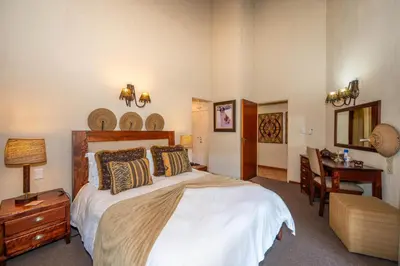 a bedroom with a bed and a desk and a table at Kruger Park Lodge Unit No. 246 in Hazyview