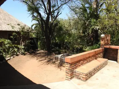 a brick retaining wall with a bench in a yard at Collin's Rest in Marloth Park