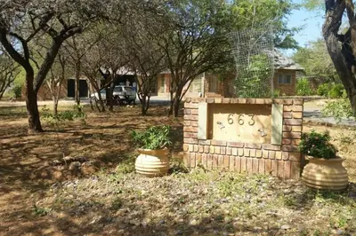 a stone grave in a yard with two potted plants at Collin's Rest in Marloth Park