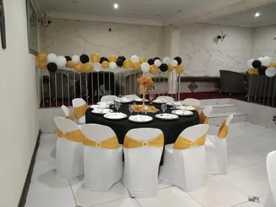 a table with white chairs and black and yellow balloons at Ecotel Midrand in Midrand