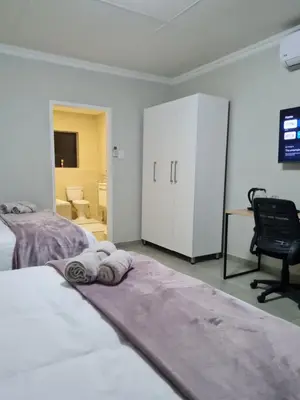 a bedroom with two beds and a desk and a chair at Lukhanyo Guest House in Northam