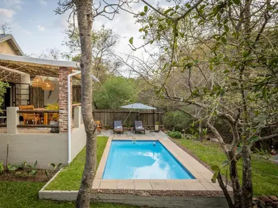 a swimming pool in a yard next to a house at The Blyde Canyon House in Hoedspruit
