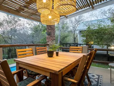 a wooden table with chairs and a chandelier at The Blyde Canyon House in Hoedspruit