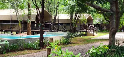 a resort building with two swimming pools and trees at Tot Hier Toe in Phalaborwa