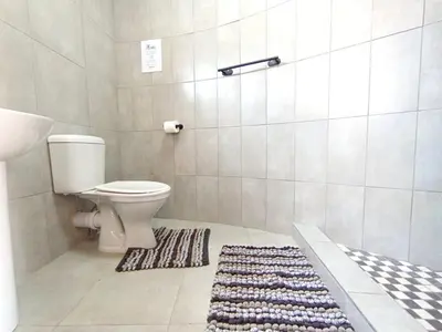 a bathroom with a toilet and a rug at OR Tambo Stay Unit 3 in Boksburg