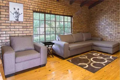 a living room with two couches and a brick wall at Lilly’s-place in Sabie