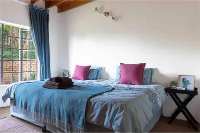 a bedroom with a bed with pink and blue sheets at Lilly’s-place in Sabie
