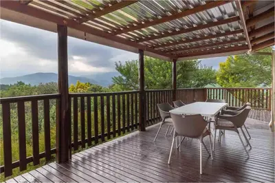 a patio with a table and chairs on a deck at Lilly’s-place in Sabie