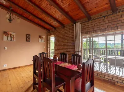 a dining room with a table and a large window at Lilly’s-place in Sabie