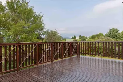 a wooden railing on a wooden deck with trees at Lilly’s-place in Sabie