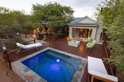 a backyard with a swimming pool and a wooden deck at Africa House in Hoedspruit