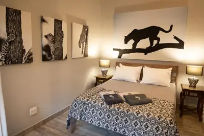 a bedroom with a bed with a cheetah on the wall at Africa House in Hoedspruit