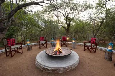 a fire pit with chairs and candles in a yard at Africa House in Hoedspruit