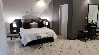 a bedroom with a large bed with white sheets and pillows at Siesta Guest House in Musina