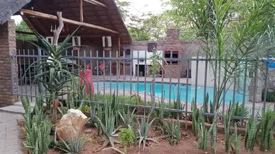 a fence around a swimming pool in front of a house at Siesta Guest House in Musina