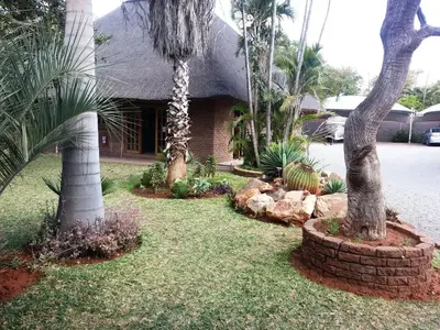 a yard with palm trees and a house at Siesta Guest House in Musina