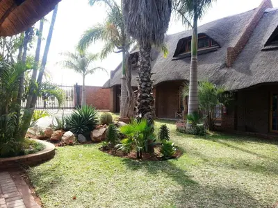 a yard with palm trees and a house at Siesta Guest House in Musina