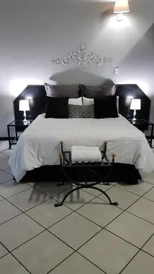 a bedroom with a large bed with two tables and two lamps at Siesta Guest House in Musina
