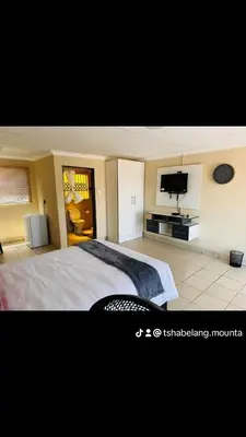 a bedroom with a bed and a flat screen tv at TSHABELANG MOUNTAIN VIEW LODGE in Burgersfort