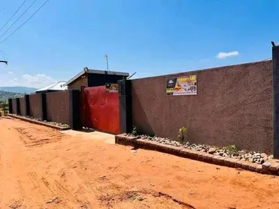 a building with a red door next to a dirt road at TSHABELANG MOUNTAIN VIEW LODGE in Burgersfort