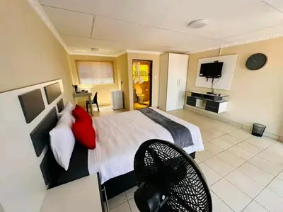 a bedroom with a large bed and a television at TSHABELANG MOUNTAIN VIEW LODGE in Burgersfort
