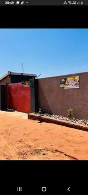 a building with a red door next to a dirt field at TSHABELANG MOUNTAIN VIEW LODGE in Burgersfort