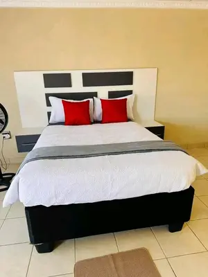 a bedroom with a large bed with two red pillows at TSHABELANG MOUNTAIN VIEW LODGE in Burgersfort