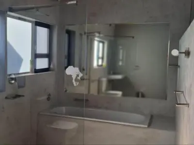 a bathroom with a tub and a large mirror at Tswenyane Kruger Lodge in Marloth Park