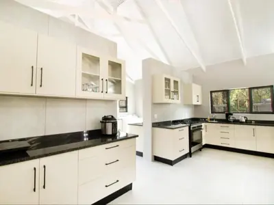 a large kitchen with white cabinets and black counter tops at Tswenyane Kruger Lodge in Marloth Park