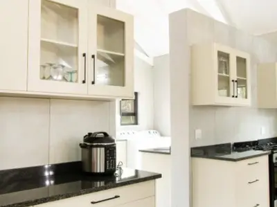 a kitchen with white cabinets and a slow cooker at Tswenyane Kruger Lodge in Marloth Park