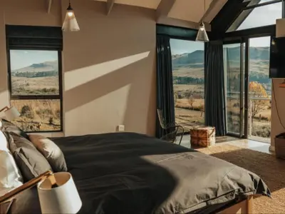 a bedroom with a large bed and large windows at Sensiri Myst Country House in Dullstroom