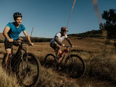 two men are riding bikes in a field at Sensiri Myst Country House in Dullstroom