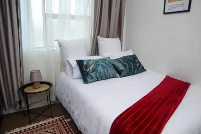 a bedroom with a white bed with pillows and a window at Spacious and luxury 3 bedroom apartment in Midrand