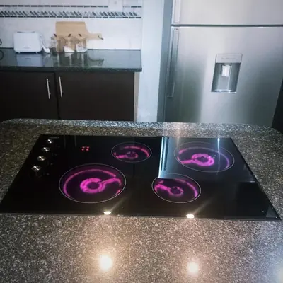 a stove top oven with purple flames on a kitchen counter at AZALEA LODGE in Midrand