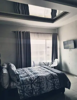 a bedroom with a bed and a window at AZALEA LODGE in Midrand