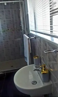 a white sink in a bathroom with a window at AZALEA LODGE in Midrand