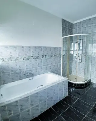 a bathroom with a white tub and a shower at AZALEA LODGE in Midrand