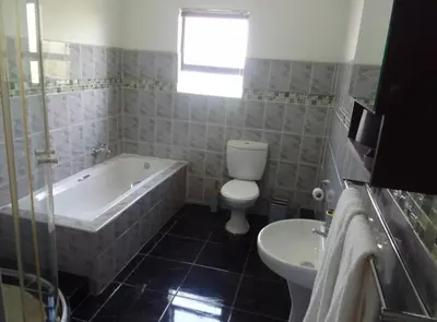 a bathroom with a tub and a toilet and a sink at AZALEA LODGE in Midrand