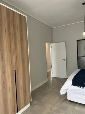 a bedroom with a bed and a wooden cabinet at Large 3 Bedroom Apartment in Midrand, Waterfall City - More space than a hotel room - Ideal for families, groups and work trips - 19 Elizabeth Place in Midrand