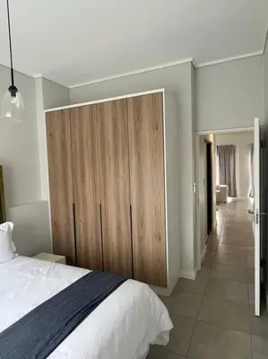 a bedroom with a bed and a large wooden cabinet at Large 3 Bedroom Apartment in Midrand, Waterfall City - More space than a hotel room - Ideal for families, groups and work trips - 19 Elizabeth Place in Midrand
