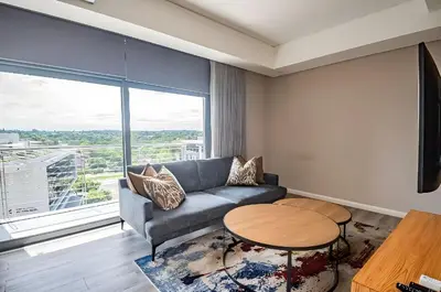 a living room with a couch and a table and a large window at Menlyn Maine Residences 1 bedroom Apartment 505 in Pretoria