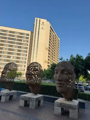 two statues of heads sitting on benches in front of buildings at Menlyn Maine Residences 1 bedroom Apartment 505 in Pretoria