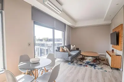 a living room with a couch and a table and chairs at Menlyn Maine Residences 1 bedroom Apartment 505 in Pretoria
