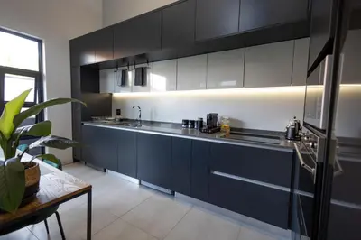 a kitchen with black and white cabinets and a table at Luxurious Upmarket Apartment in Pretoria