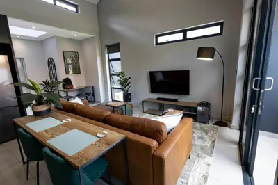 a living room with a couch and a tv at Luxurious Upmarket Apartment in Pretoria